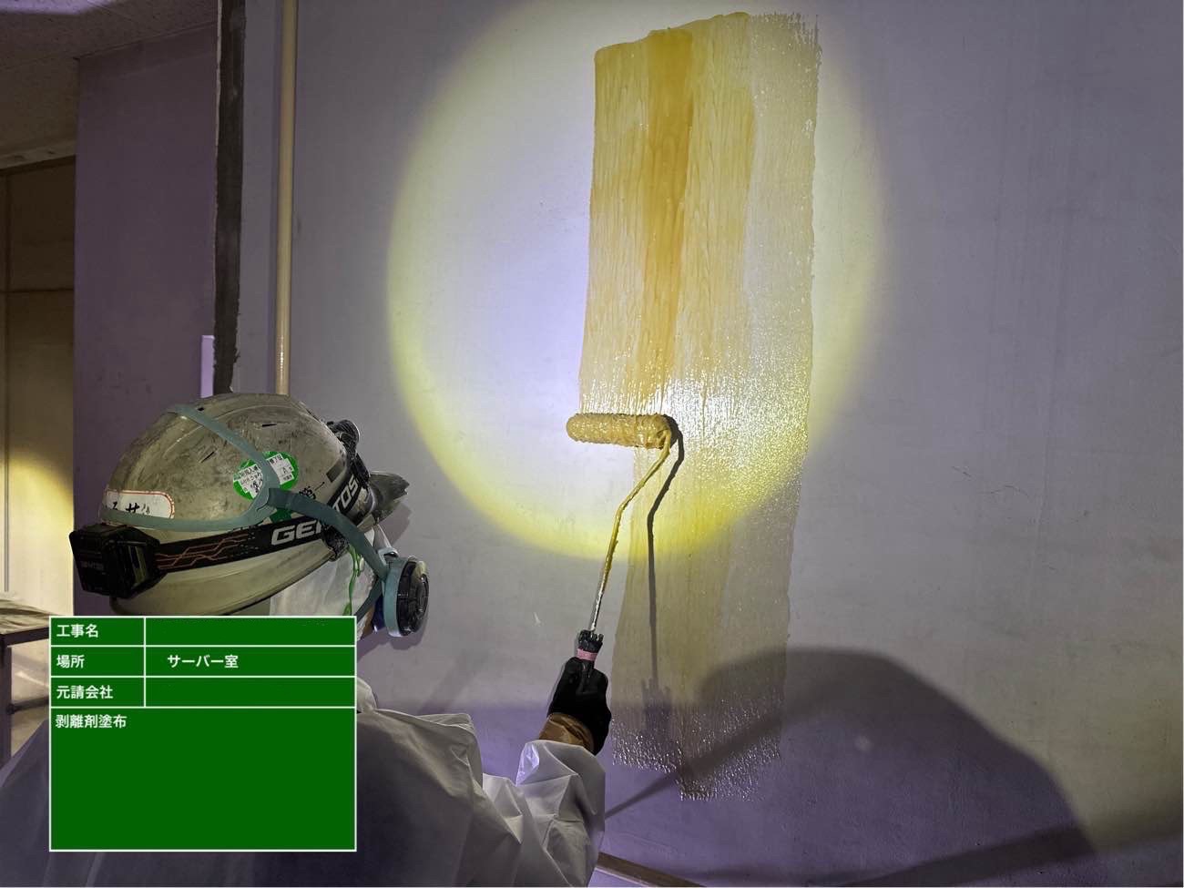 作業員が剥離剤をローラーで塗布している様子
