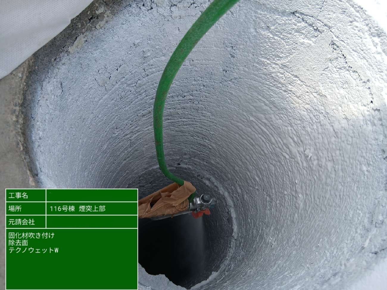 煙突内部の除去面にホースを挿入し、固化材を噴霧している様子