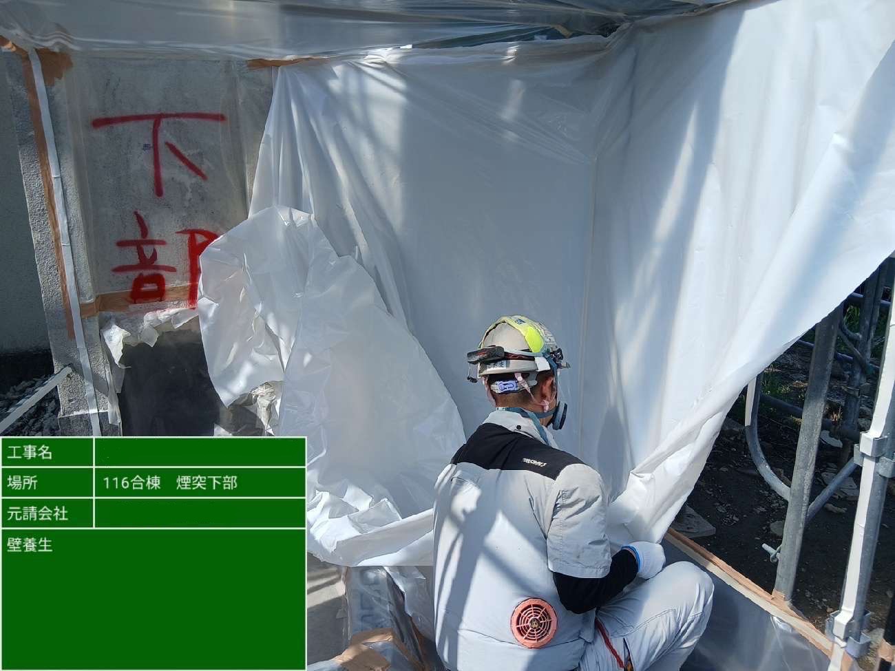 壁面にシートを張り養生している作業員の様子