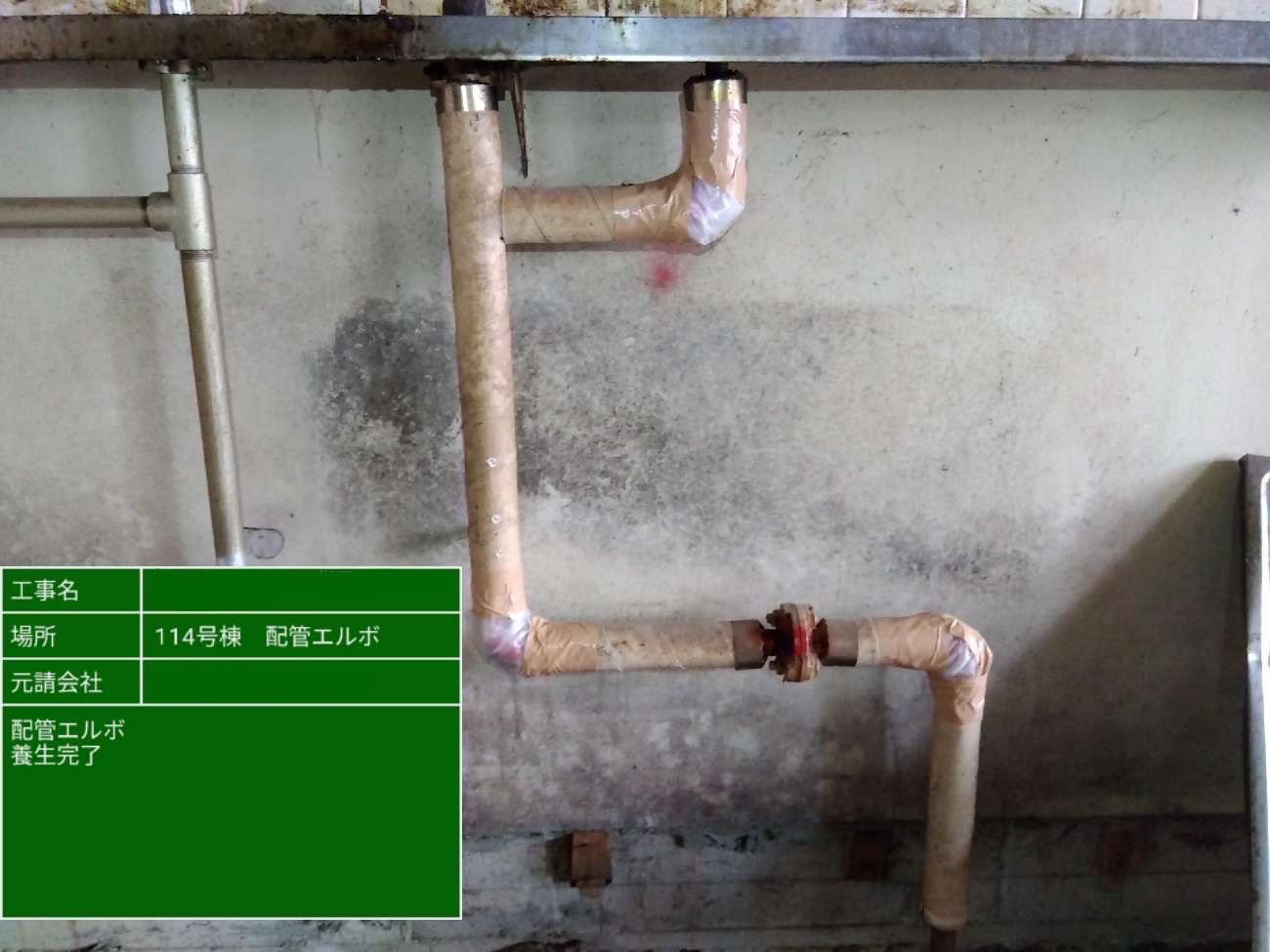 配管エルボ部分にテープを巻き、アスベスト飛散防止のためのシート養生を行う作業員の手元