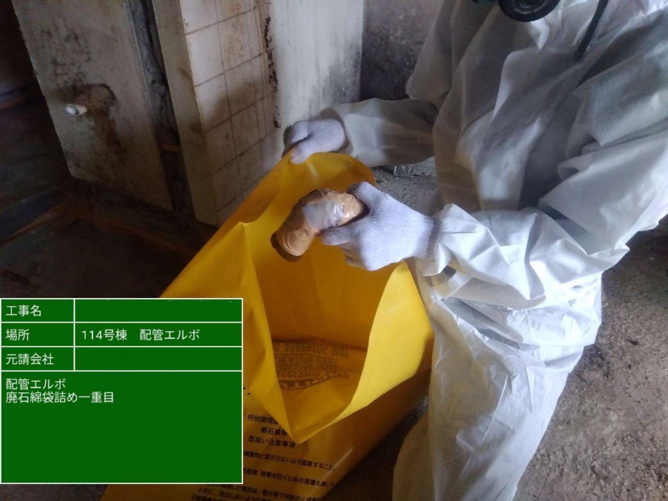 切断された配管エルボを黄色アスベスト専用袋に丁寧に封入する作業員