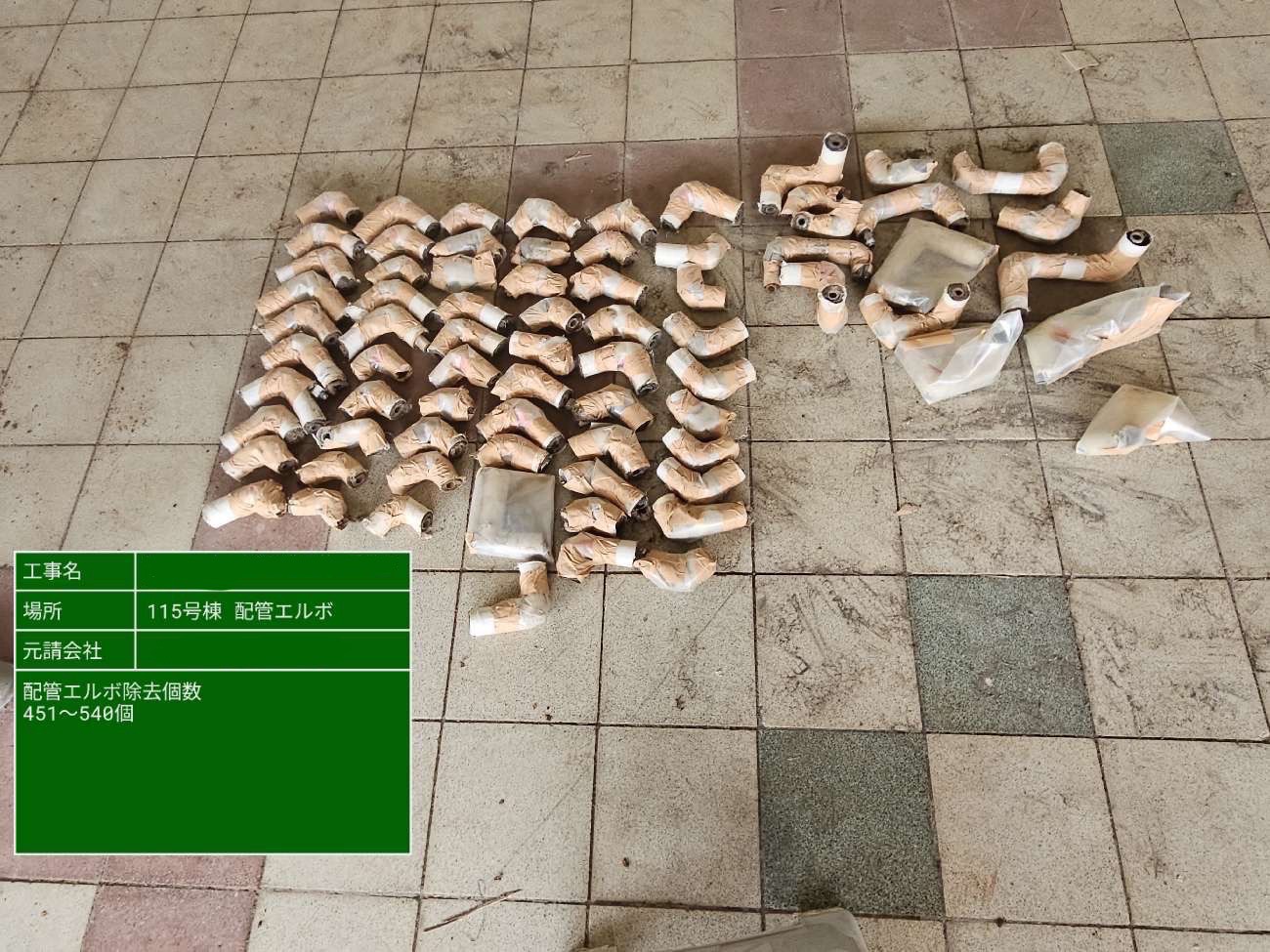 切断・撤去されたアスベスト含有配管エルボ約50個を床に整然と並べた写真