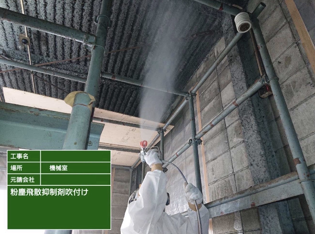 機械室の天井に粉塵飛散抑制剤を吹き付ける作業員