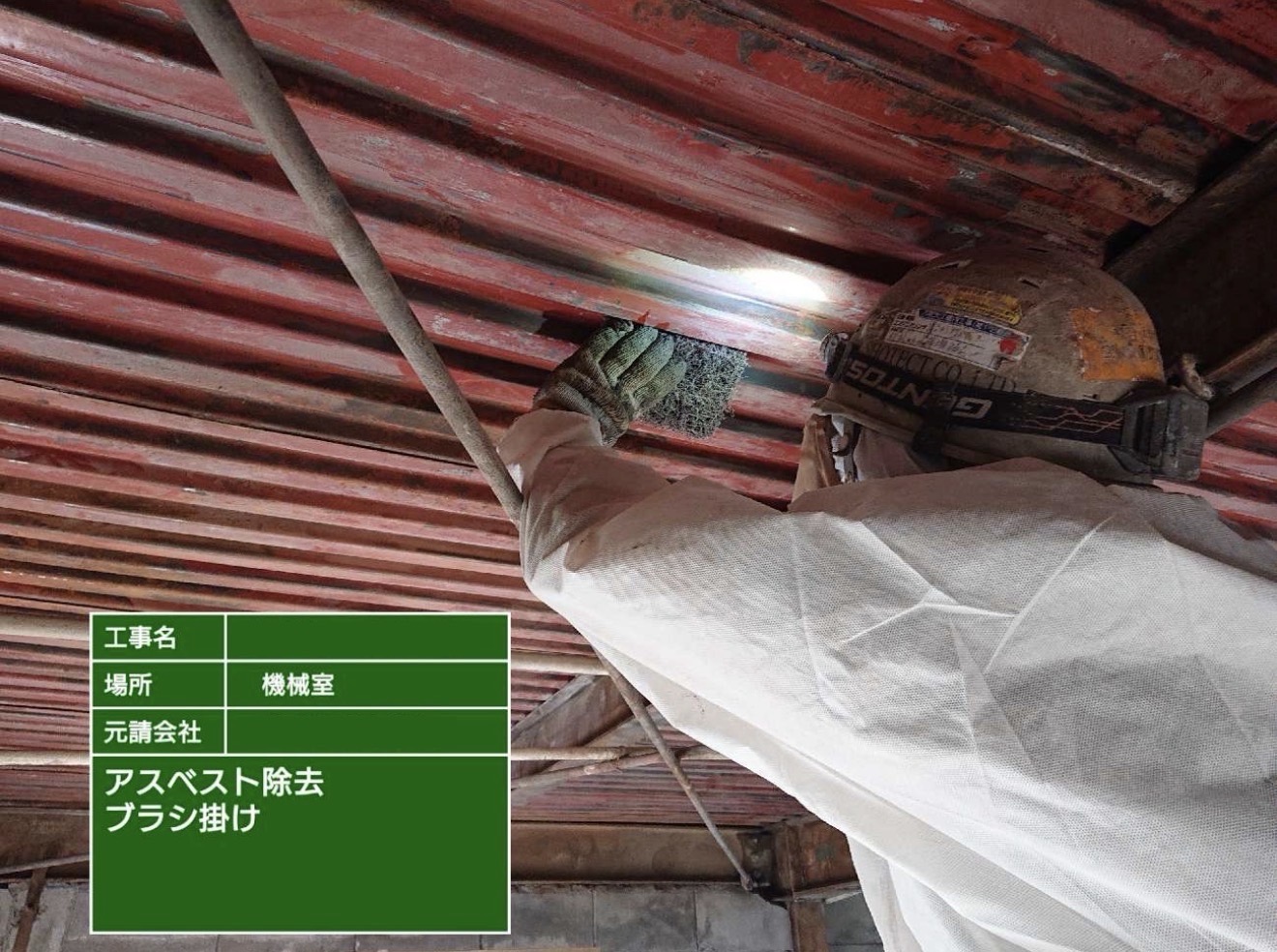 アスベスト除去後の天井をブラシで清掃する作業員